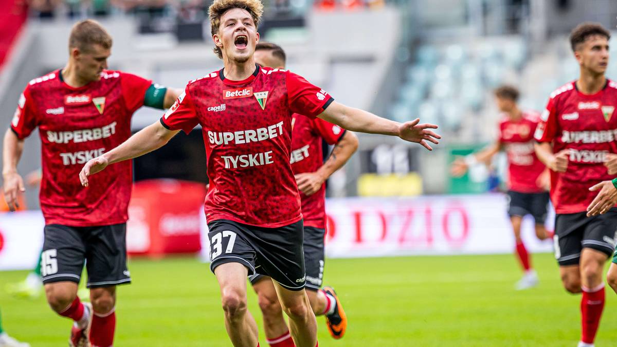 Piłkarze GKS Tychy w czerwonych strojach biegają po boisku, jeden z nich z numerem 37 świętuje.