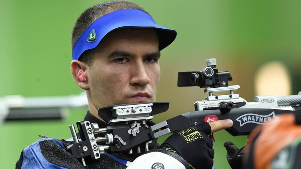 Tomasz Bartnik, polski strzelec sportowy, w pozycji strzeleckiej, celuje przez lunetę karabinu sportowego.