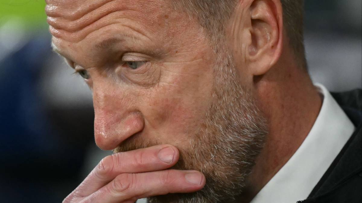 Mężczyzna w średnim wieku ze zamyśloną miną i ręką na ustach.