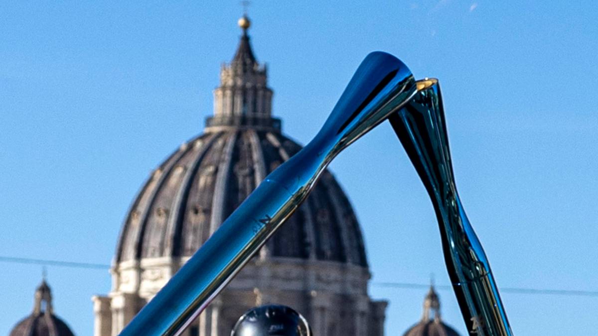 Pochodnia olimpijska z płomieniem na tle kopuły Bazyliki Świętego Piotra w Rzymie.