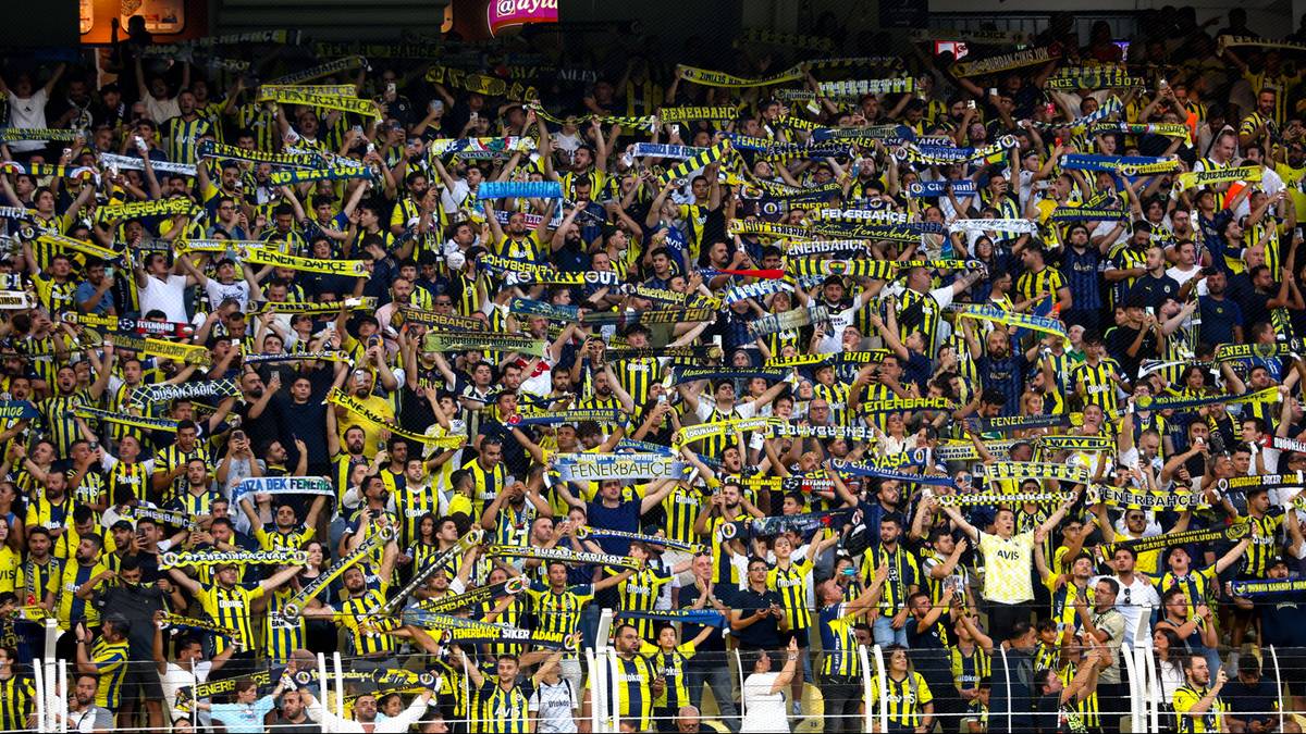 Tłum kibic&oacute;w Fenerbah&ccedil;e na trybunach stadionu, trzymających szaliki.