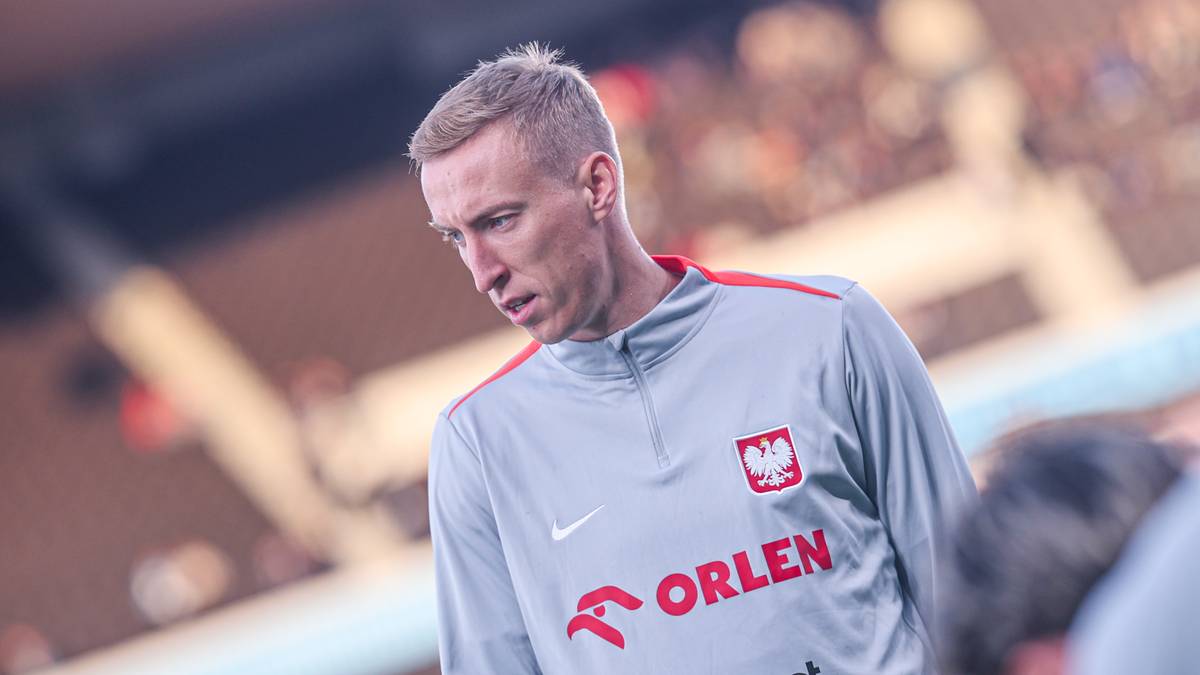 Piłkarz w szarej koszulce z orłem polskim i logiem ORLEN.
