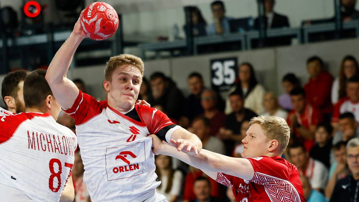 Gracz w biało-czerwonej koszulce z numerem 87 próbuje rzucić piłkę do bramki, podczas gdy jego przeciwnik próbuje go zablokować.