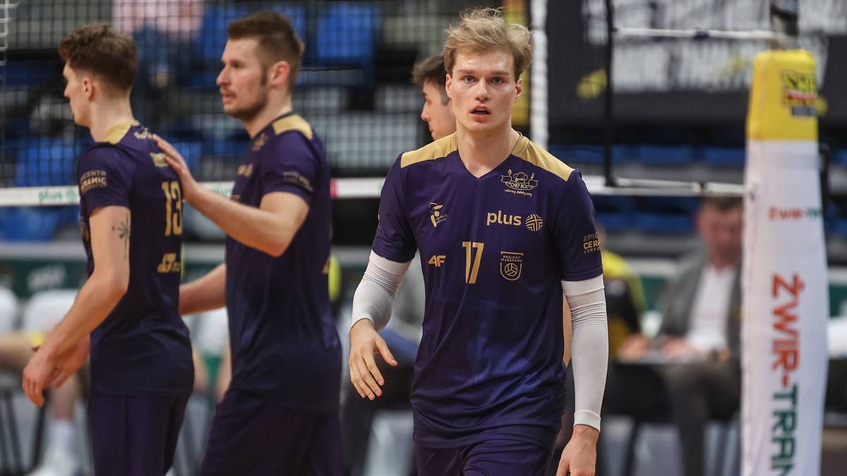 Siatkarze w ciemnofioletowych strojach sportowych na boisku.