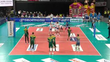 Boisko do siatk&oacute;wki z zawodnikami w trakcie meczu, otoczone trybunami z publicznością.