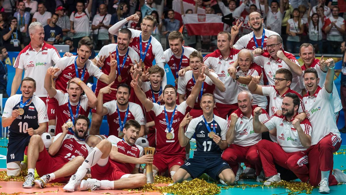 Reprezentacja Polski w siatkówce mężczyzn świętująca zdobycie złotego medalu mistrzostw świata, pozująca do grupowego zdjęcia z pucharem.