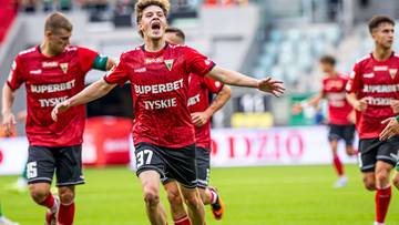 Piłkarze GKS Tychy w czerwonych strojach biegają po boisku, jeden z nich z numerem 37 świętuje.