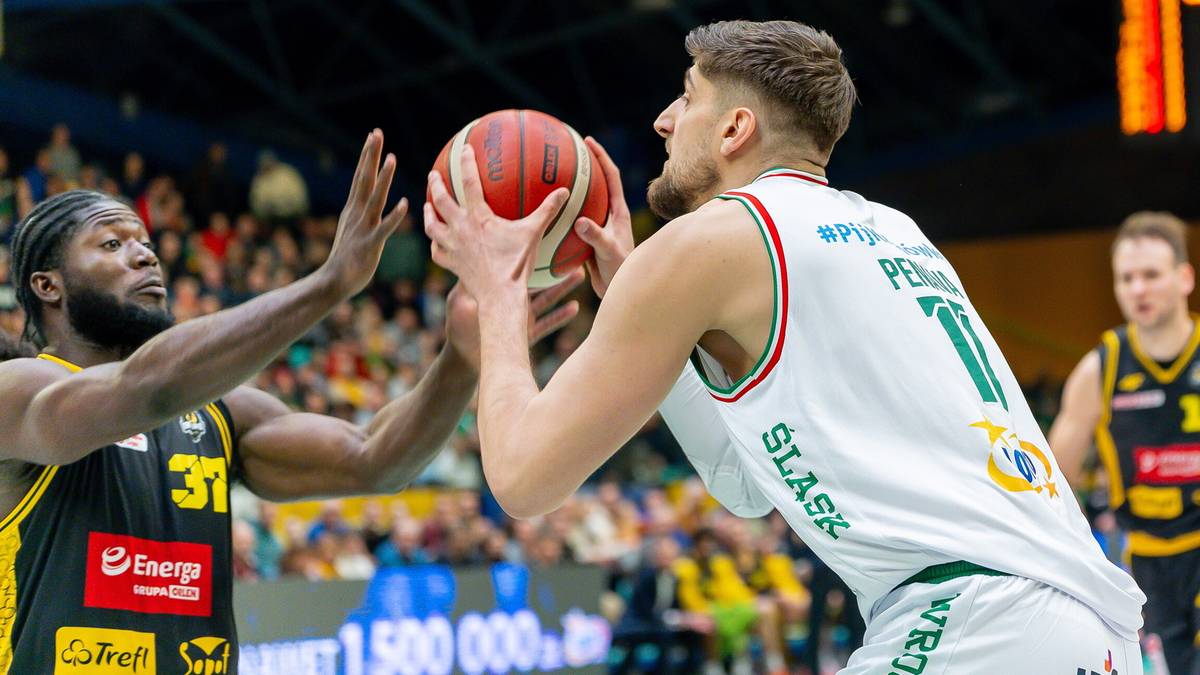 Gracz Śląska Wrocław trzyma piłkę do koszyk&oacute;wki, podczas gdy obrońca pr&oacute;buje mu ją odebrać.