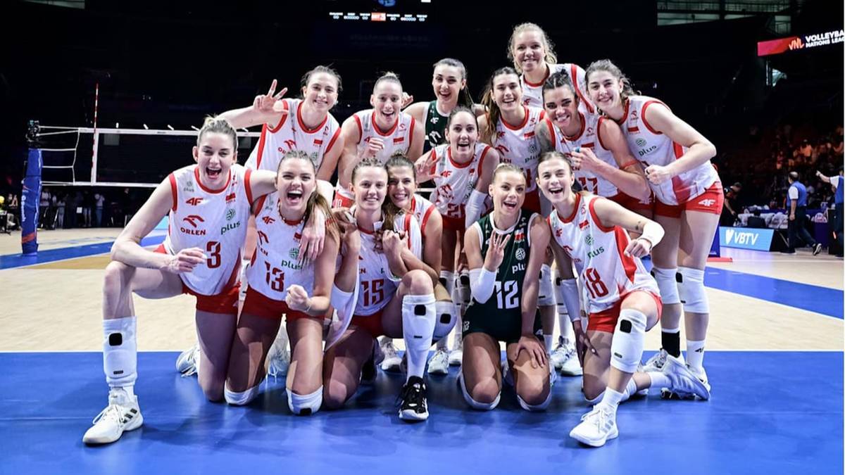 Zdjęcie grupowe reprezentacji Polski w siatkówce kobiet, stojące i klęczące, uśmiechające się i pozujące do fotografii po zwycięstwie.