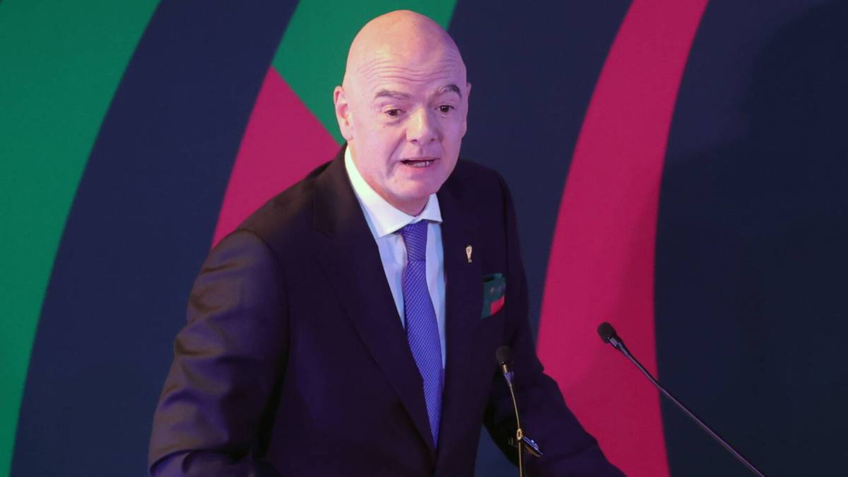 Gianni Infantino w garniturze przemawia za m&oacute;wnicą.