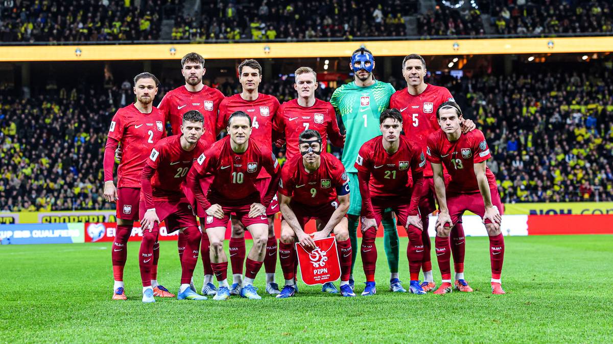 Drużyna piłkarska w czerwonych strojach na tle stadionu.