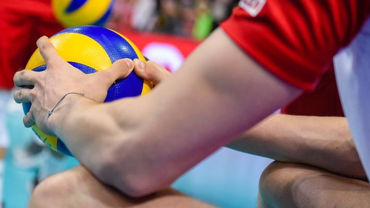 Siatkarz trzyma piłkę do siatk&oacute;wki