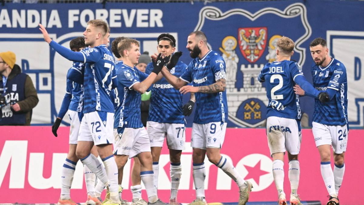 Piłkarze Lecha Poznań w niebieskich strojach cieszą się po strzelonym golu na boisku.