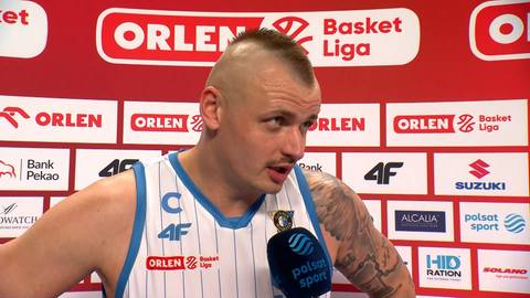 Koszykarz udzielający wywiadu przed ścianką z logotypami Orlen Basket Liga.