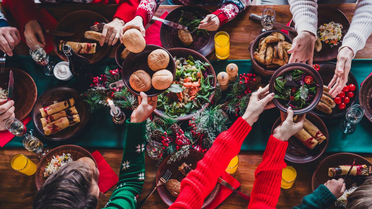 Ludzie siedzący przy świątecznym stole podczas posiłku, jedzący i pijący.