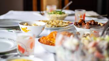 Stół nakryty do wigilijnej kolacji, pełen potraw i talerzy, sugerujący wspólne świętowanie.