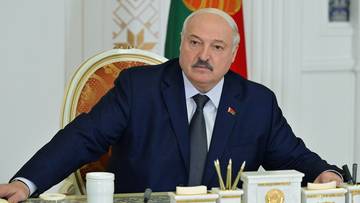 Aleksandr Łukaszenka, prezydent Białorusi, siedzi przy biurku w garniturze.