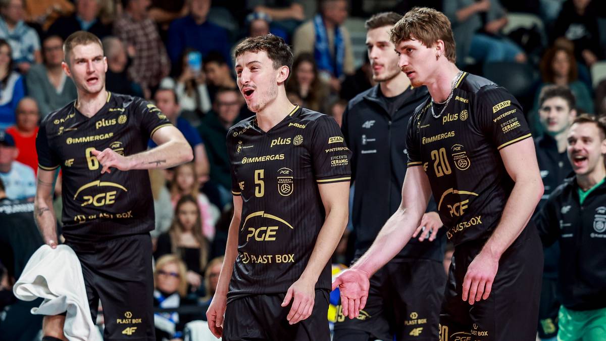 Czterech siatkarzy PGE Projekt Warszawa w czarnych strojach z ż&oacute;łtymi napisami stoi na boisku, jeden z nich podaje rękę koledze.