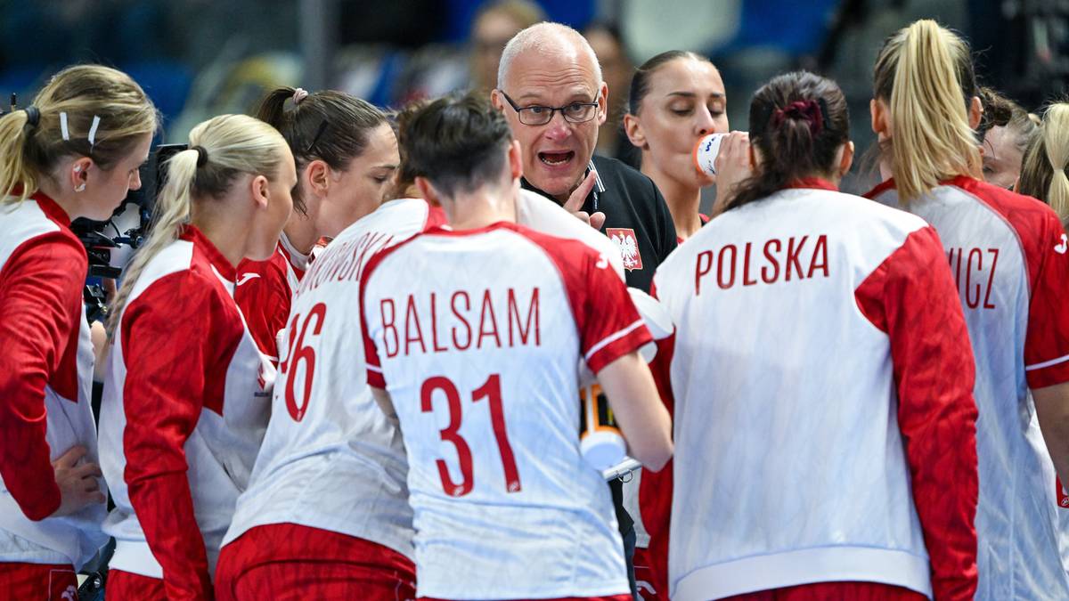 Trener w okularach zwraca się do grupy piłkarek ręcznych reprezentacji Polski, które stoją wokół niego w białoczerwonych strojach.