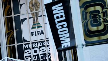 Logo FIFA World Cup 2026 z Pucharem Świata w tle i czarną flagą z napisem "WELCOME".