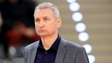 Mężczyzna w garniturze, trener siatkówki, z powagą na twarzy.