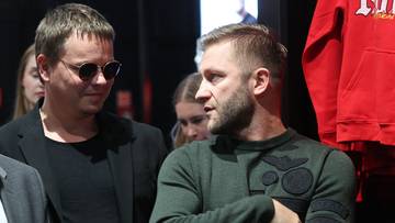 Dw&oacute;ch mężczyzn rozmawia, jeden w okularach przeciwsłonecznych, drugi z brodą.