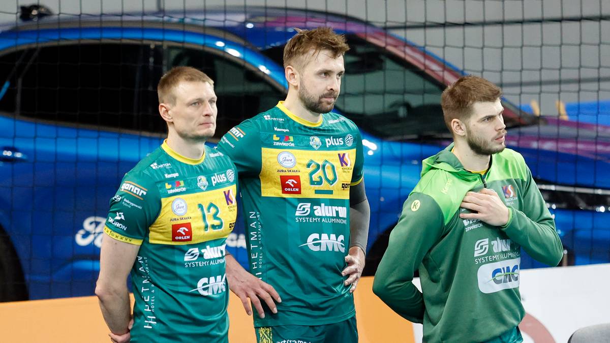 Trzech siatkarzy w zielonych strojach z numerami na plecach.