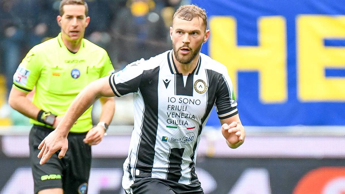 Piłkarz w czarno-białej koszulce sportowej z numerem "37" biegnie po boisku, z opaską kapitańską na ramieniu. Za nim widać sędziego w ż&oacute;łtej koszulce.