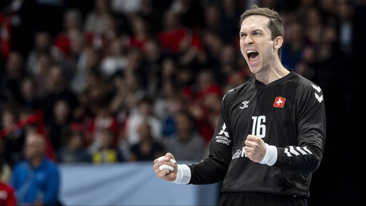Bramkarz w czarnej koszulce z numerem 16 i flagą Szwajcarii, świętuje z zaciśniętymi pięściami i otwartymi ustami.