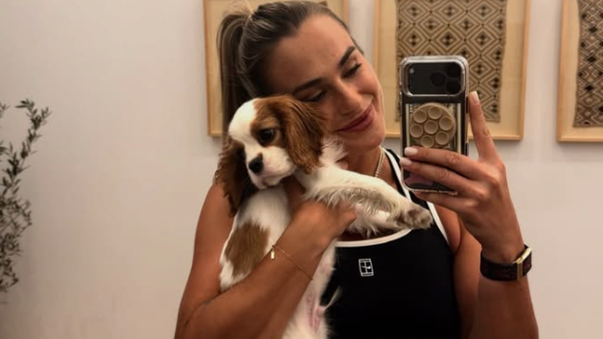 Aryna Sabalenka trzyma w ramionach szczeniaka cavalier king charles spaniel i robi sobie selfie.