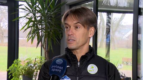 Piotr Szczypka, mężczyzna w czarnej kurtce z logo, m&oacute;wi do mikrofonu Polsat Sport.