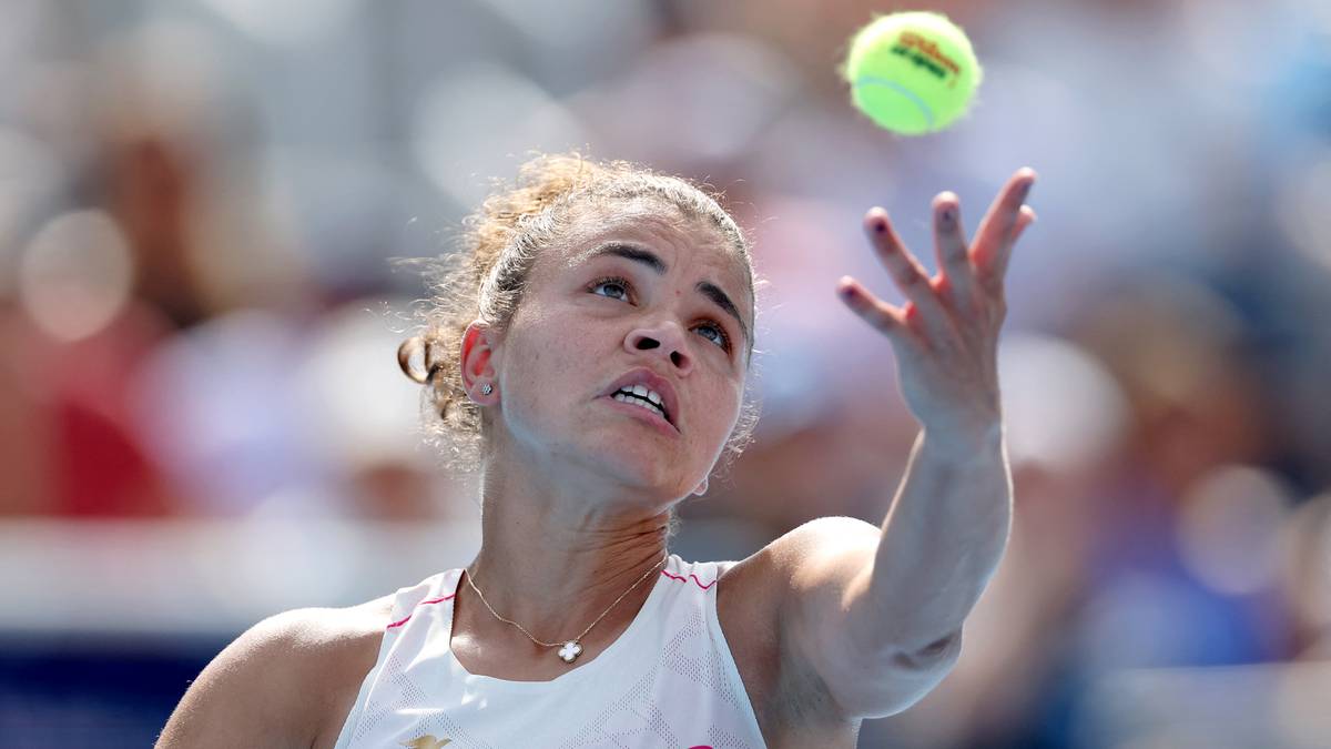 Tenisistka Jasmine Paolini podczas serwisu, koncentrując się na piłce do tenisa unoszącej się nad jej głową.