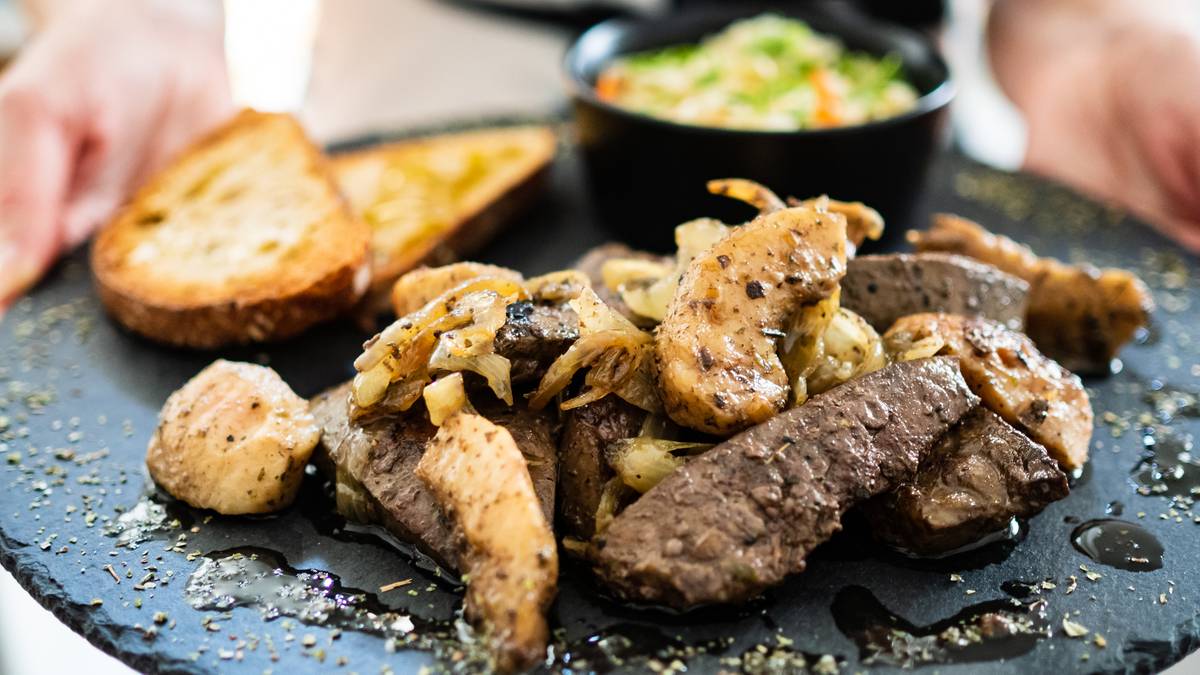 Talerz pełen duszonych podrob&oacute;w z dodatkiem grzanek i sałatki.