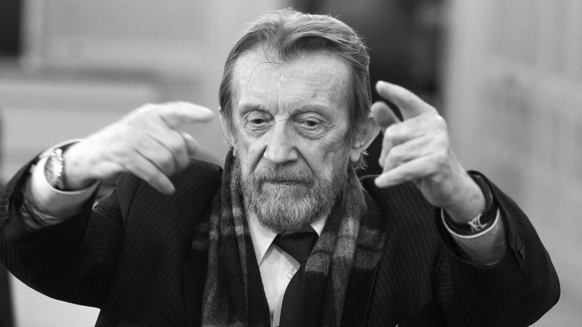 Starszy mężczyzna z brodą gestykuluje.