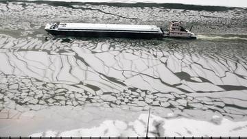 Polska barka uwięziona na zamarzniętej rzece w pobliżu Poczdamu, z widocznym holownikiem pr&oacute;bującym ją uwolnić.