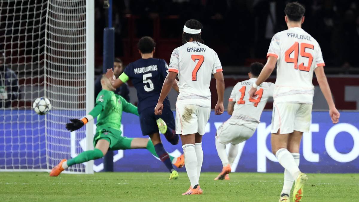 Gracze PSG i Bayernu Monachium rywalizują o piłkę w polu karnym, bramkarz próbuje obronić strzał.