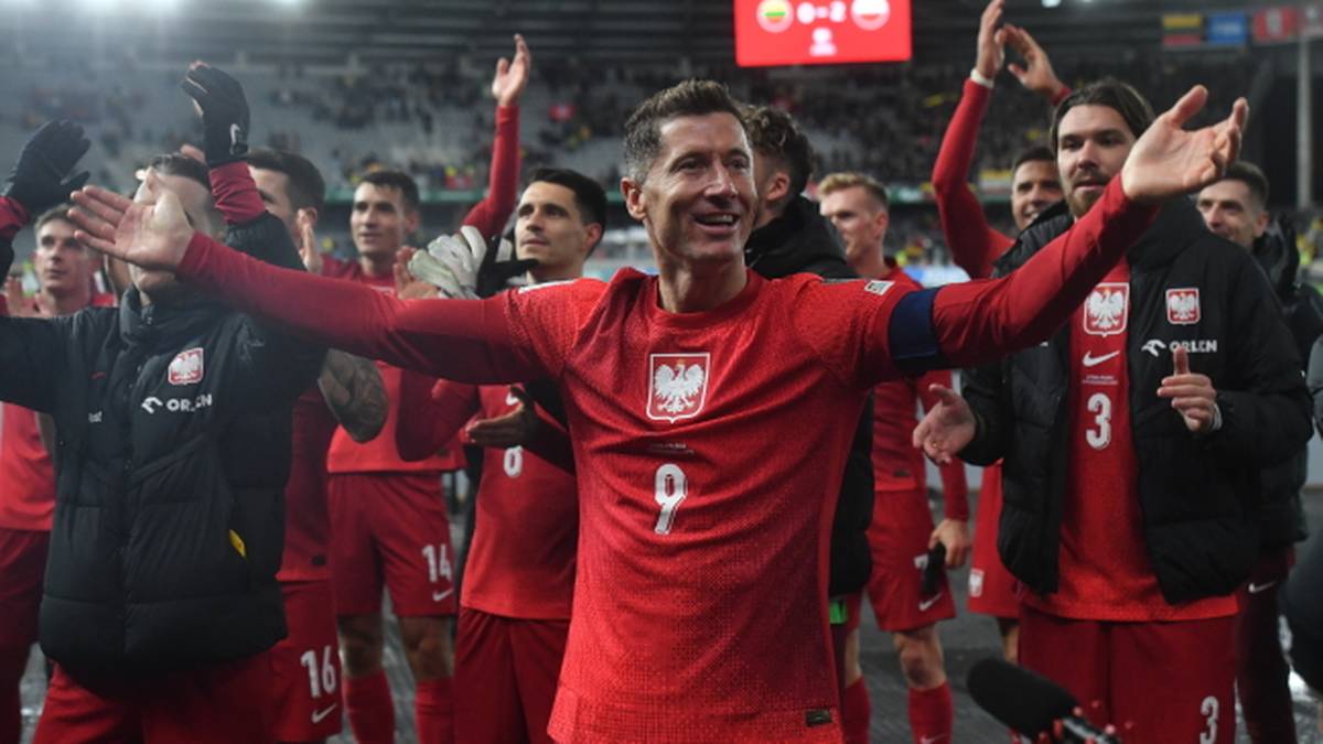 Piłkarze reprezentacji Polski w czerwonych strojach świętują z podniesionymi rękami, Robert Lewandowski w centrum.