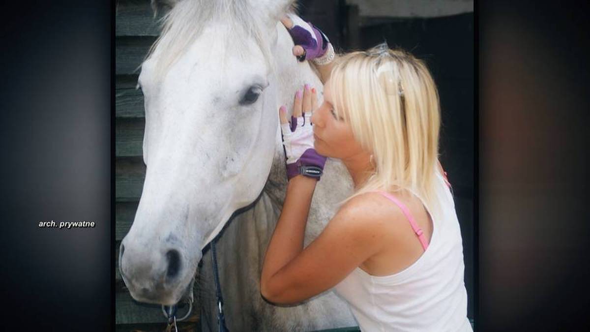 Kobieta w rękawiczkach do jazdy konnej przytula białego konia.