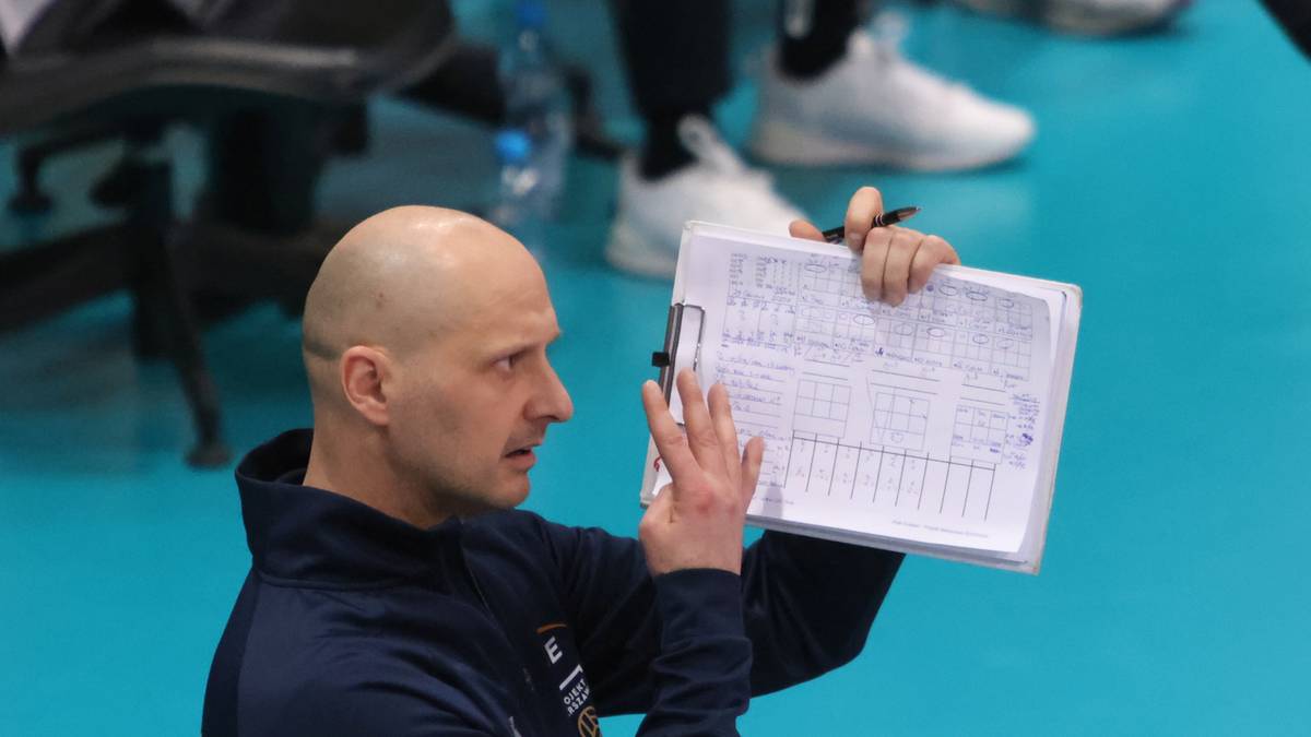 Trener siatk&oacute;wki pokazuje notatki na kartce papieru.