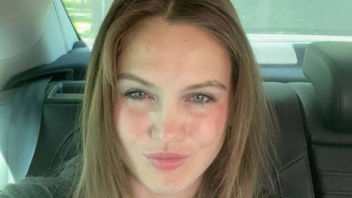 Młoda kobieta z jasnymi włosami i niebieskimi oczami robi selfie w samochodzie, patrząc wprost do obiektywu z lekko przymkniętymi ustami.