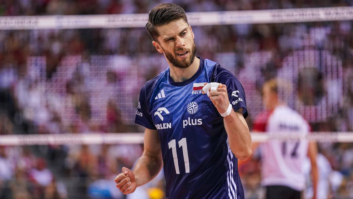 Siatkarz Aleksander Śliwka w niebieskiej koszulce z numerem 11, triumfuje podczas meczu.