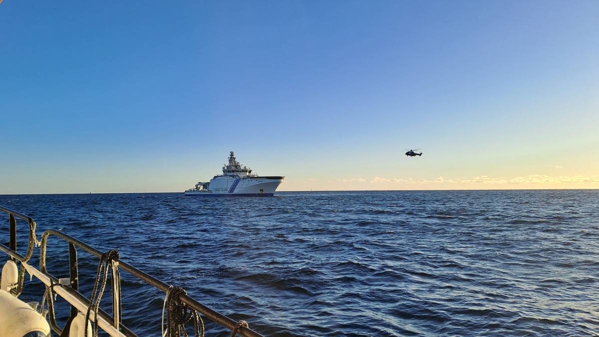 Widok statku towarowego na morzu przy zachodzącym słońcu.
