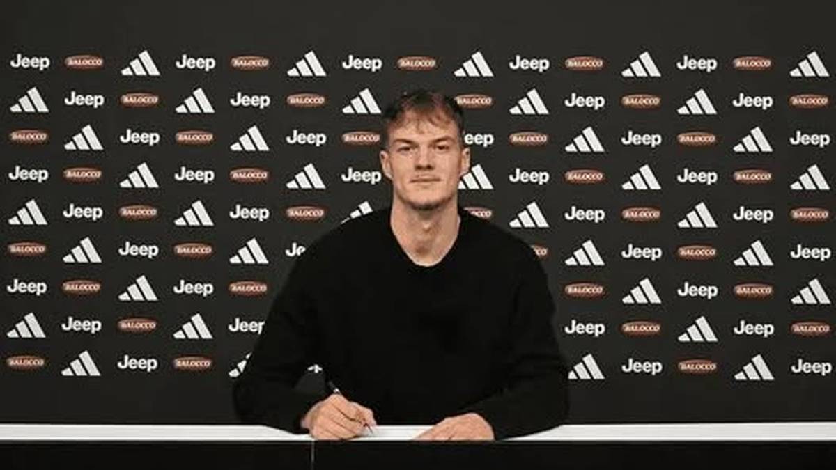 Piłkarz Patryk Mazur siedzi przy stole i podpisuje dokumenty na tle logo Juventusu.