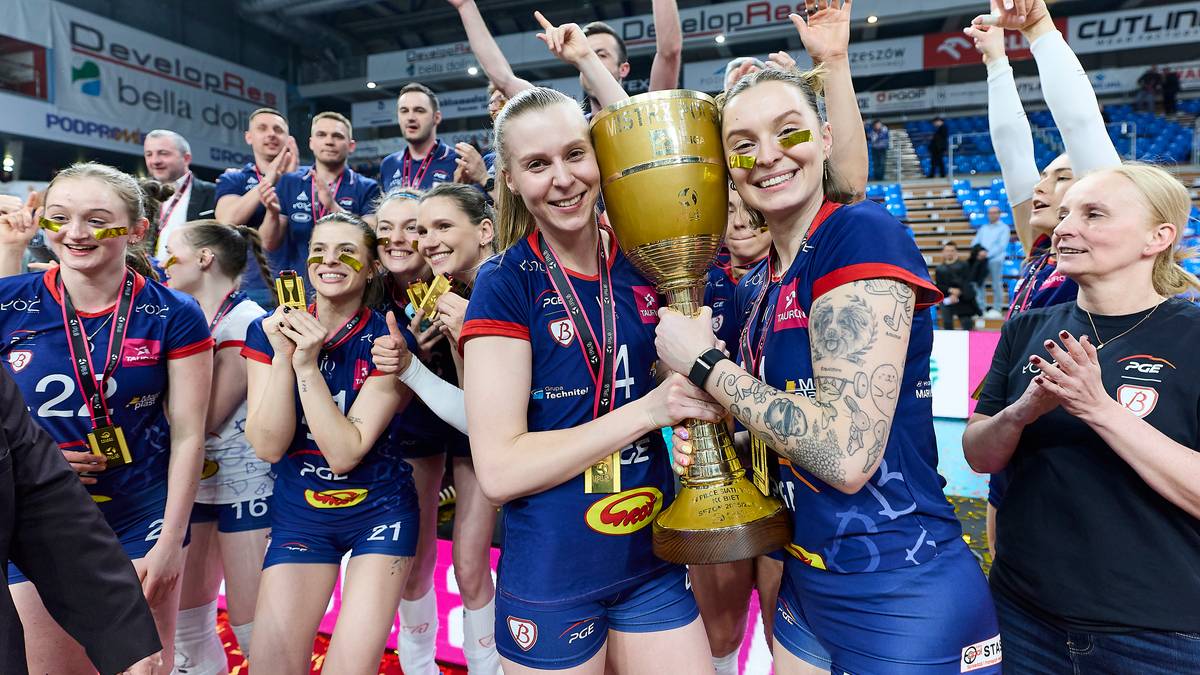 Siatkarki celebrują zdobycie pucharu, trzymając go wsp&oacute;lnie.