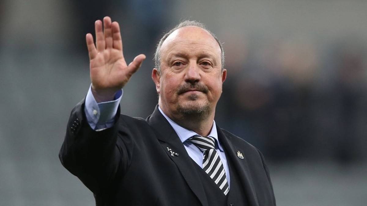 Portret Rafaela Beníteza, mężczyzny w średnim wieku w czarnym garniturze, pozdrawiającego publiczność uniesioną ręką.