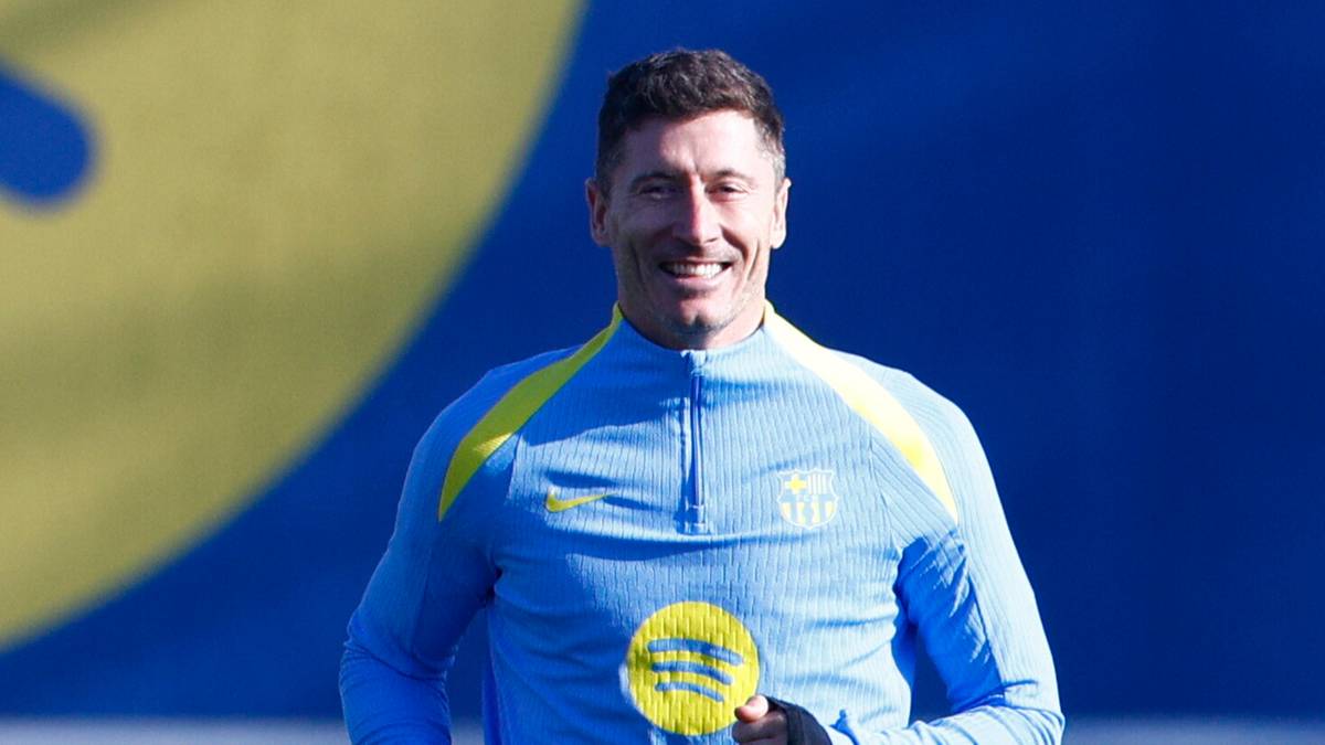 Piłkarze w jasnoniebieskich strojach treningowych biegają po boisku piłkarskim.