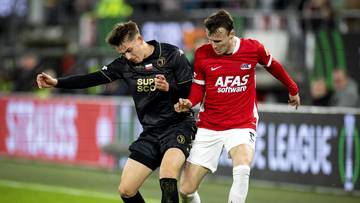 Dwóch piłkarzy walczących o piłkę na boisku podczas meczu.