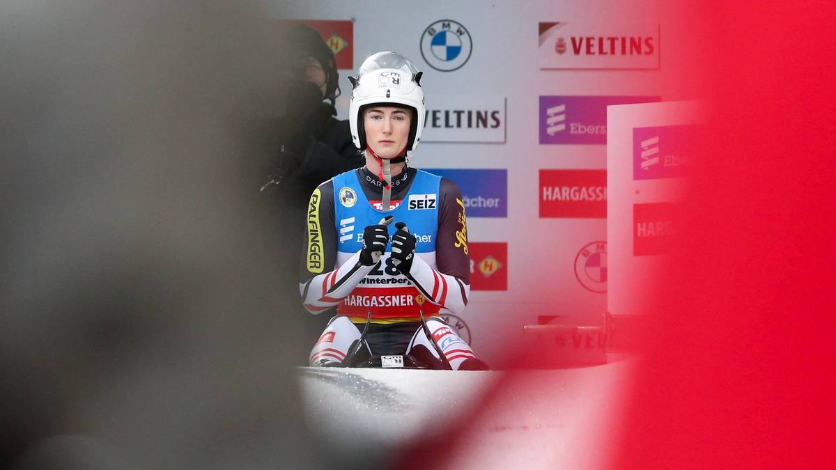 Sportsmenka w kasku i stroju sportowym siedzi na saneczkach, gotowa do zjazdu.