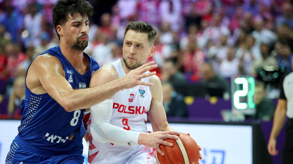 Dwóch koszykarzy podczas meczu, jeden w białej koszulce z napisem 'Polska' broni drugiego w niebieskiej koszulce z numerem '8'.