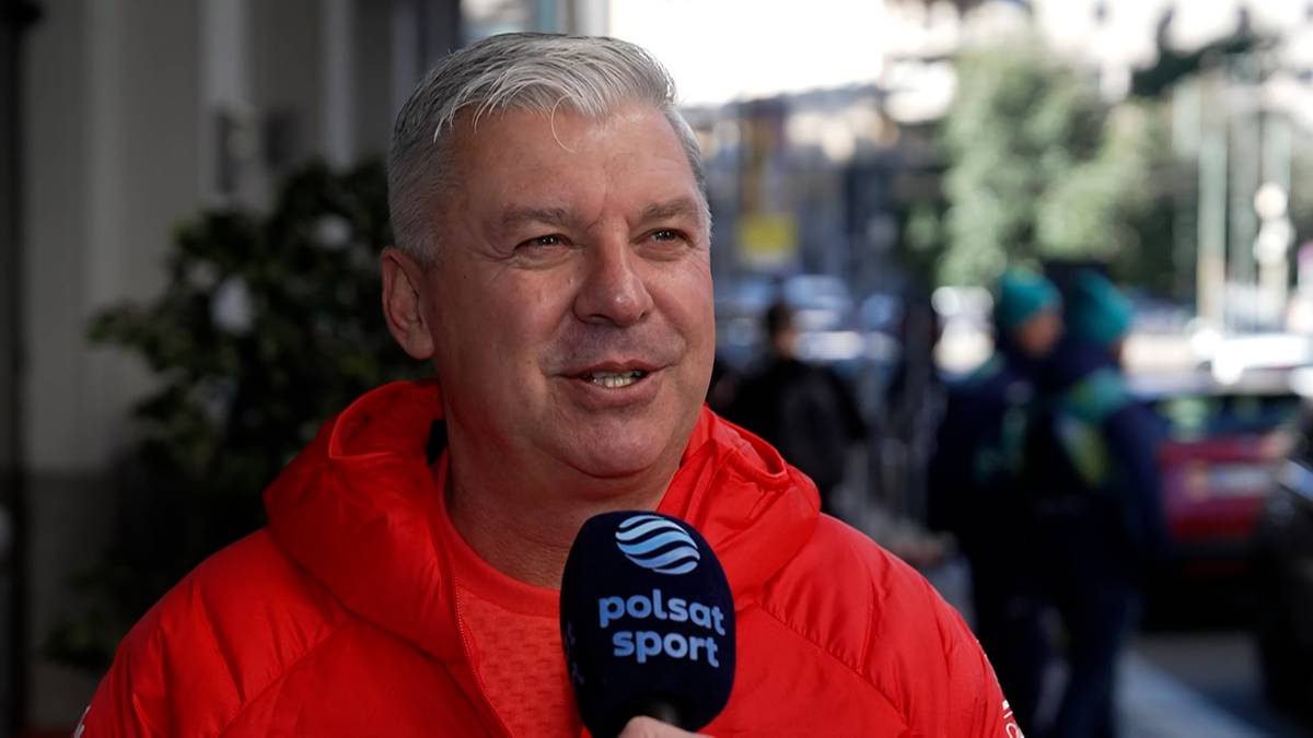Tomasz Chamera w czerwonej bluzie z kapturem, m&oacute;wiący do mikrofonu Polsat Sport.